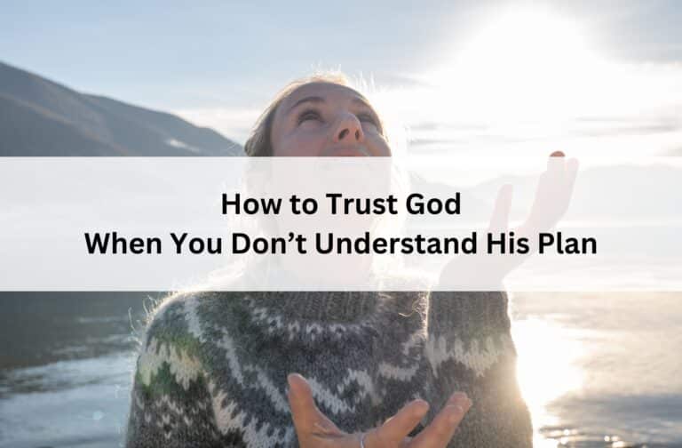 Woman looking up with open hands by a lake at sunrise, wearing a cozy sweater, with text overlay: “How to Trust God When You Don’t Understand His Plan.”