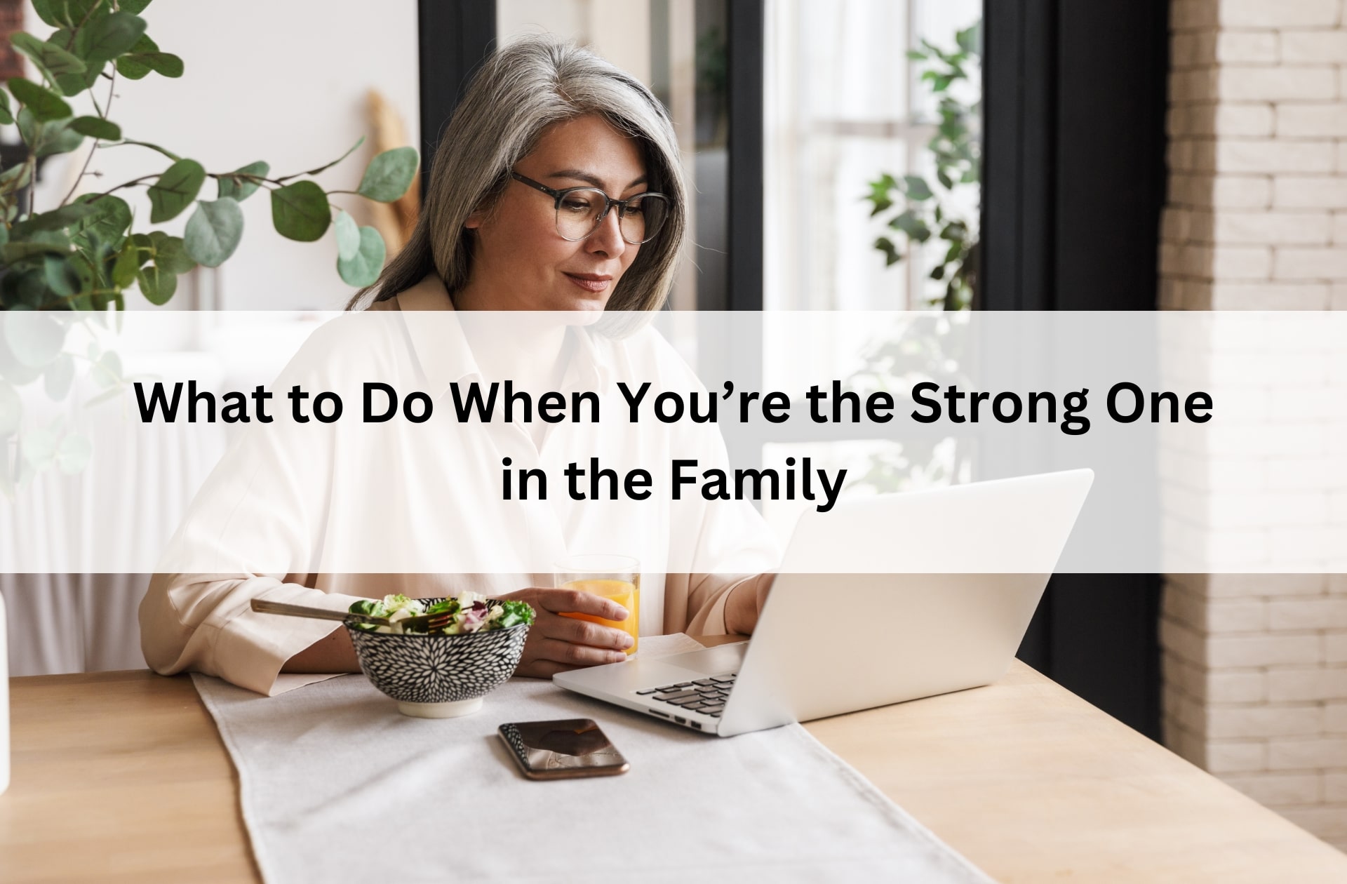 Woman working on a laptop at the kitchen table, symbolizing strength, caregiving, and finding support when you carry your family’s burdens.